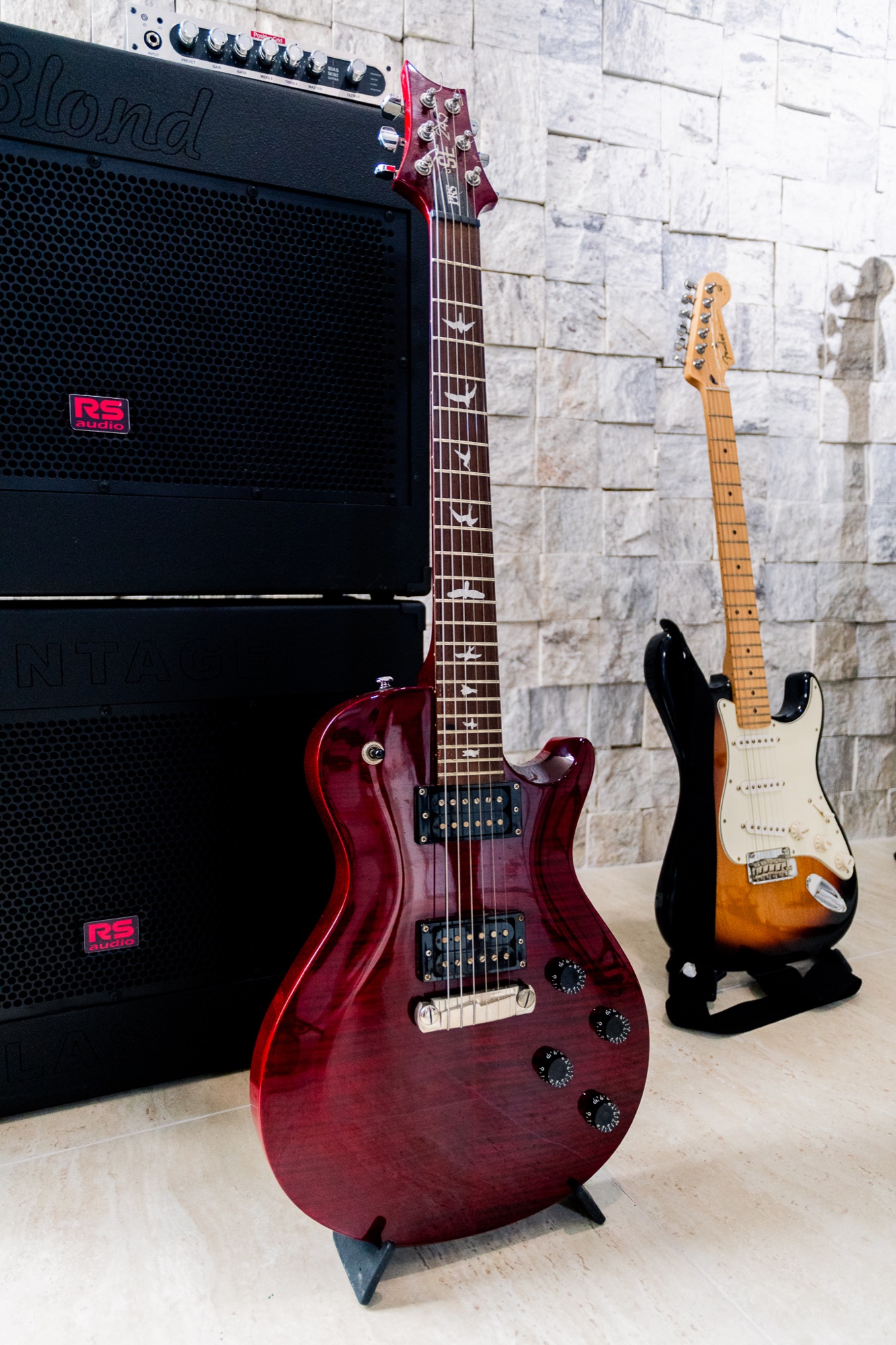 Guitarras apoiadas diante dos amplificadores da Casa Krás